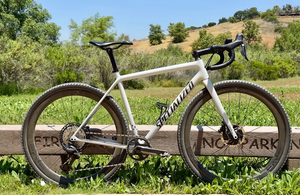 Specialized Crux gravel bike leaning on a fence rail in front of golden hills